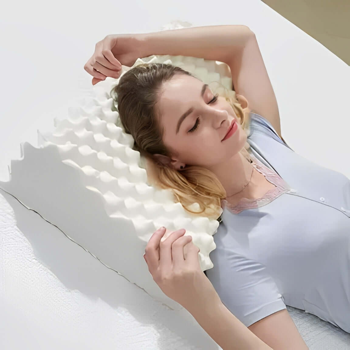 Woman relaxing with a pillow massager, enjoying comfort and relaxation on a soft bed.